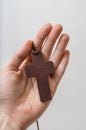 Hand holds brown cross. Religion concept