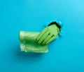 Hand holds a bundle of transparent garbage bags on a blue background. A part of the body sticks out of a torn hole in the paper Royalty Free Stock Photo