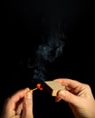 A hand holds burning match on black background. A wooden match burns in the hands of a macro. Igniting a match on a box. Smoke Royalty Free Stock Photo