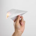 A hand holds a burning paper airplane. Close up. Isolated on a gray background Royalty Free Stock Photo