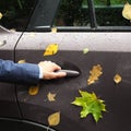 Hand holds car door handle, yellow autumn foliage and water drop Royalty Free Stock Photo