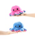 The hand holds a cheerful and sad soft toy. Happy and sad octopus. Close up. Isolated on a white background