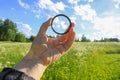 Hand holds a circular polarizer filter on field background. Royalty Free Stock Photo