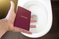 Hand holds the citizen`s passport over the toilet, throw out his passport. Concept - change of citizenship, loss of passport, pol Royalty Free Stock Photo