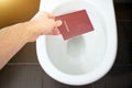 Hand holds the citizen`s passport over the toilet, throw out his passport. Concept - change of citizenship, loss of passport, pol Royalty Free Stock Photo