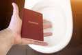 Hand holds the citizen`s passport over the toilet, throw out his passport. Concept - change of citizenship, loss of passport, pol Royalty Free Stock Photo