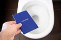 Hand holds the citizen`s passport over the toilet, throw out his passport. Concept - change of citizenship, loss of passport, pol Royalty Free Stock Photo