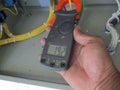 a hand holds a clamp meter displaying a voltage reading Royalty Free Stock Photo