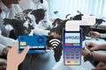 Hand holds a credit card near the payment terminal on the background of the world map and people sitting at the table. Contactless Royalty Free Stock Photo