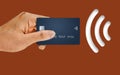 A hand holds a credit card next to a NFC near field communication or wi-fi icon