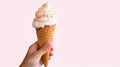 Hand holds delicious vanilla ice cream cone on a pink background with copy space. Generative AI