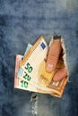 Hand holds Euro banknotes in jeans rip hole Royalty Free Stock Photo