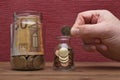 Hand holds euro coins and bill on the burgundy red background in a money box Royalty Free Stock Photo