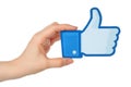 Hand holds facebook thumbs up sign printed on paper on white background