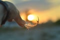 Hand holds a feather on a sunset background. Romance, dreamy mood, travel