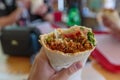 hand holds food wrapped in lavash view from the first person