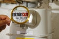 hand holds a golden magnifying glass and zoom display of the gas meter