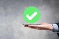 Hand holds green icon Check mark,Check Mark Sign, Tick Icon,right sign,circle green checkmark button,Done.On dark background. Royalty Free Stock Photo