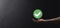 Hand holds green icon Check mark,Check Mark Sign, Tick Icon,right sign,circle green checkmark button,Done.On dark background. Royalty Free Stock Photo