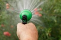 Hand holds manual sprinkler for irrigation and watering garden by water jets