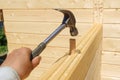 Hand holds hammer and strikes wood dowel to secure connection of wall timbers Royalty Free Stock Photo