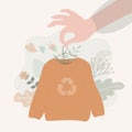 Hand holds hanger with recycled sweater. Sweatshirt made of ethnic material. Eco textile and vegan clothing