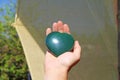 The hand holds the heart from natural stone green jade. Heart in hand. A stone in the shape of a heart. Love talisman, zen, spa