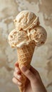 A hand holds an ice cream cone with three scoops of different flavors against a plain background Royalty Free Stock Photo
