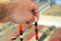 A hand holds an Islamic colorful rosary on a blurred background of a prayer rug in a mosque