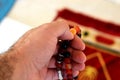 A hand holds an Islamic colorful rosary on a blurred background of a prayer rug in a mosque