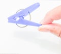 A hand holds a lavender plastic clothespin against a white background. Royalty Free Stock Photo