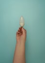 A hand holds an LED candle lamp with an E14 base on a turquoise background. Royalty Free Stock Photo