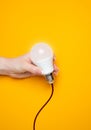 Hand holds a light bulb idea with a wire.