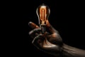 A hand holds a light bulb, providing a powerful source of illumination amidst the darkness., Robot hand holding a glowing light Royalty Free Stock Photo