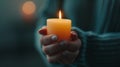 A hand holds a lit candle in a dimly lit setting Royalty Free Stock Photo