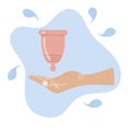 Hand holds menstrual cup on blue background. Eco-friendly, silicone washable menstrual cup. Zero waste period personal hygiene.