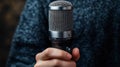 Hand holding a microphone with a mesh grill against a blurred background Royalty Free Stock Photo