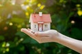 Hand holds miniature house, dreams of home ownership, in grasp Royalty Free Stock Photo