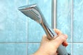 Hand holds an old shower head in bathroom