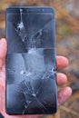 hand holds one broken large smartphone with a black screen in white cracks