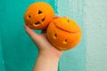 Hand holds oranges with carved faces