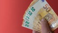 Hand holds out banknotes of 50 euros. Cash payment. Red background. copy space Royalty Free Stock Photo