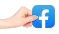 Hand holds paper Facebook mobile app icon, on transparent background. Facebook is a social media and social networking service