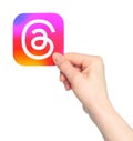 Hand holds paper Threads mobile app icon, on transparent background. Threads is an online social media and social networking Royalty Free Stock Photo