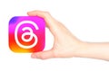 Hand holds paper Threads mobile app icon, on transparent background. Threads is an online social media and social networking Royalty Free Stock Photo