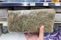 A hand holds a piece of hay in a store close-up. Food for animals in the pet store. Royalty Free Stock Photo