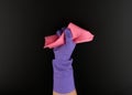 Hand holds a pink rag sponge for cleaning, protective purple rubber glove is worn on the arm Royalty Free Stock Photo