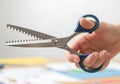Hand holding pinking shears with blue handles, ready for crafting and sewing {Ai generated Royalty Free Stock Photo