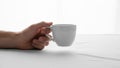 A hand holds a plain white ceramic cup against a light background Royalty Free Stock Photo