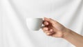 A hand holds a plain white ceramic cup against a white background Royalty Free Stock Photo